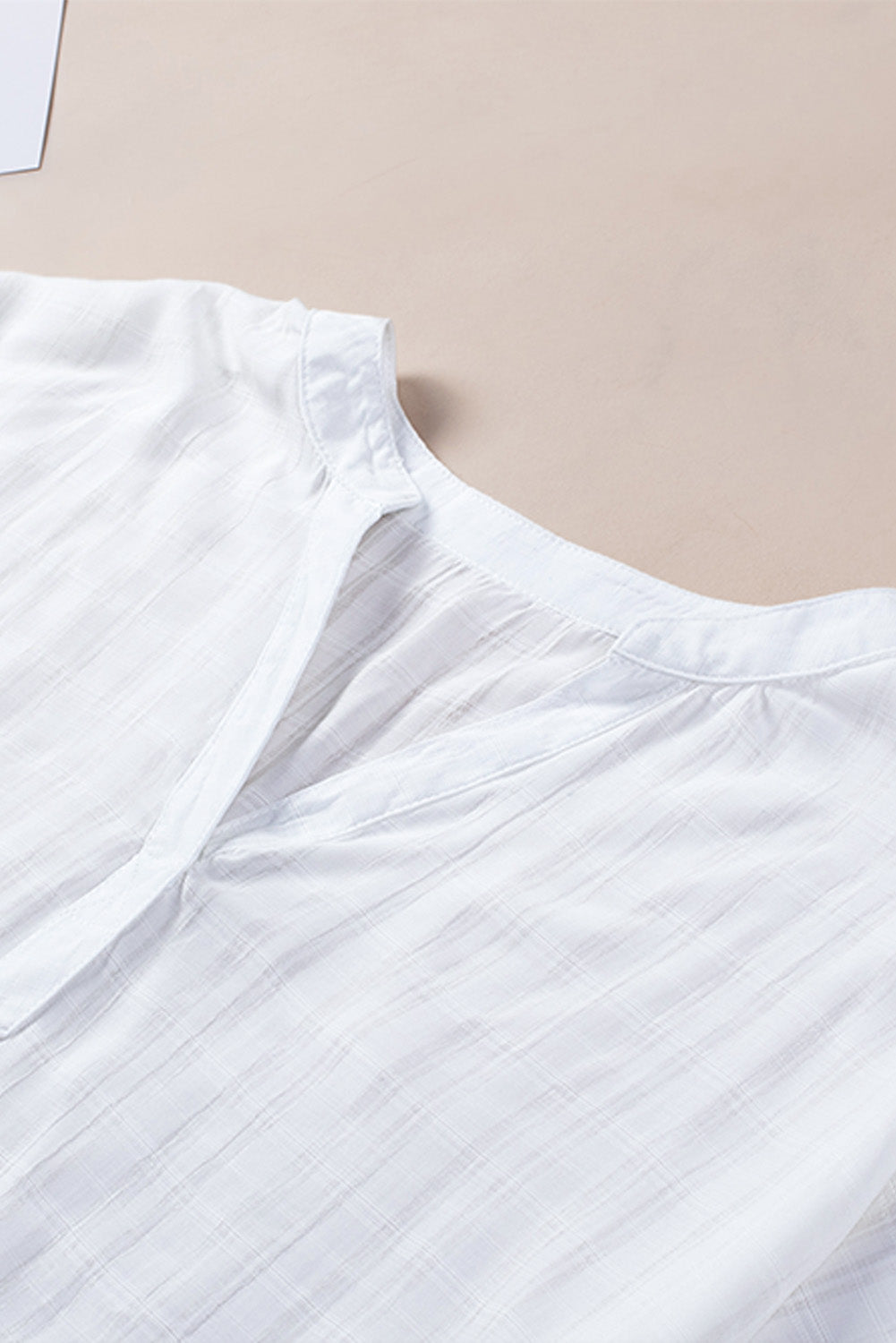 A stylish white plaid print loose V neck short sleeve shirt with slits, showcasing its trendy design and comfortable fit.