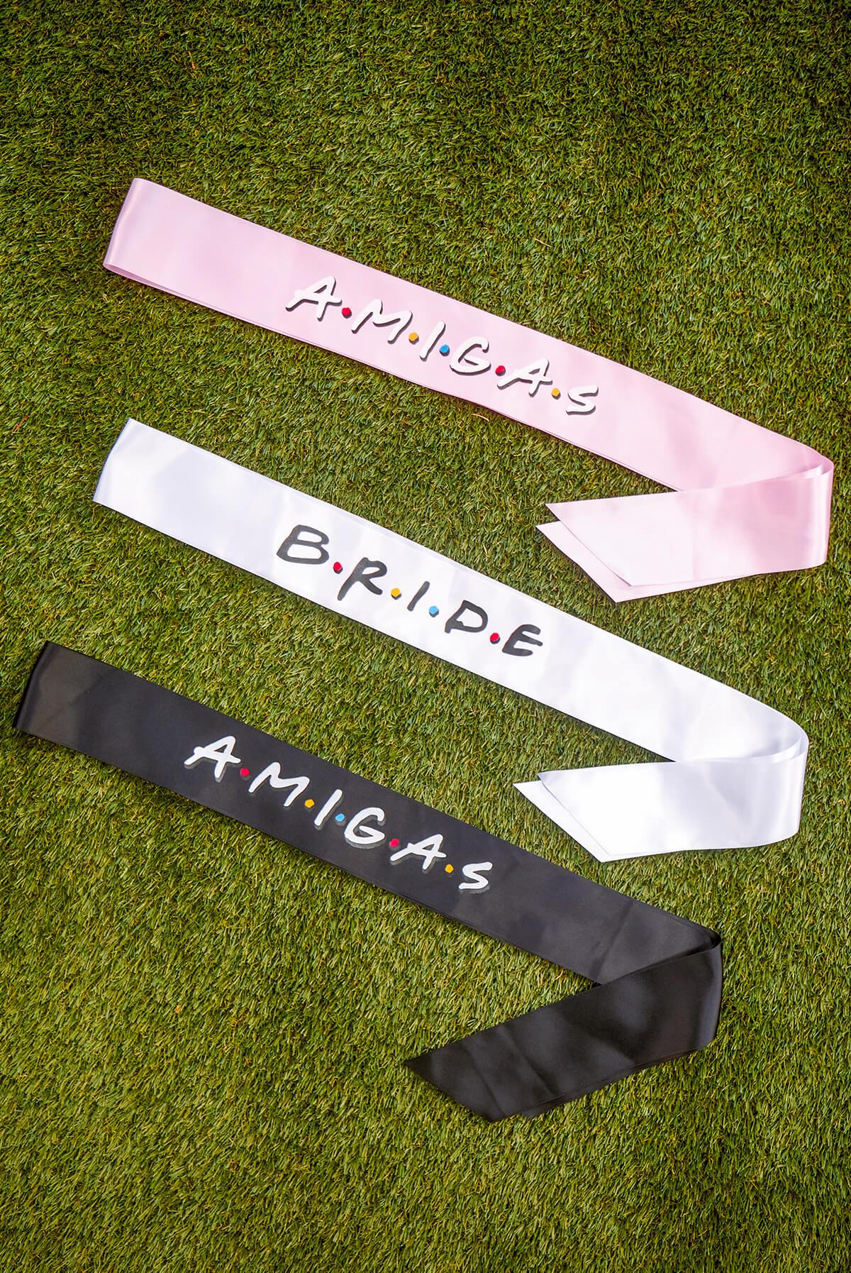 A set of FRIENDS bachelorette party sashes featuring shiny leopard foil design on white satin ribbon, perfect for brides and their amigas.
