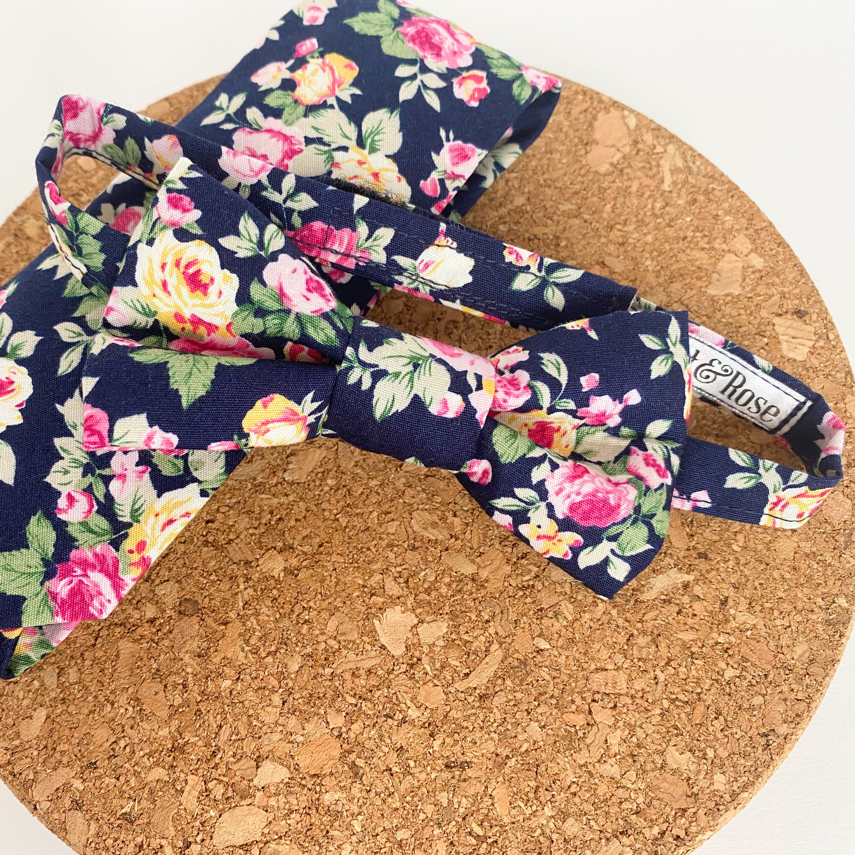 JAMESON Boys Bow Tie featuring pink and yellow roses on a navy background, handmade in England with velcro fastening.