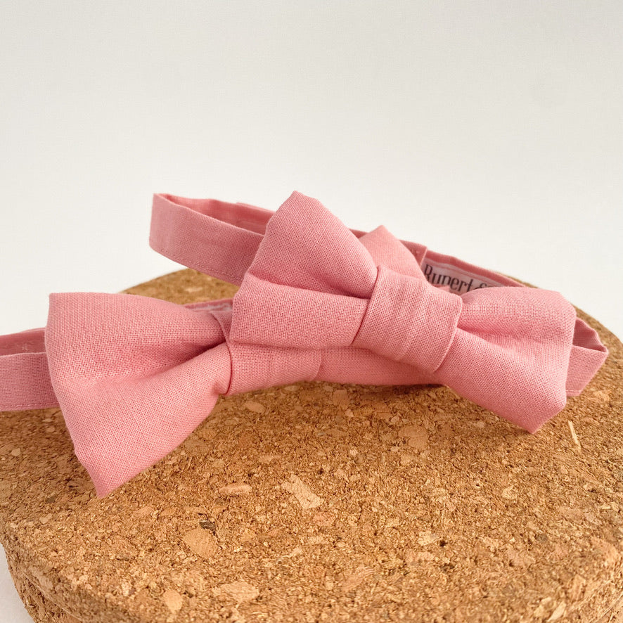A handmade pale pink boys bow tie with a velcro fastening, perfect for weddings and special occasions, displayed on a white background.