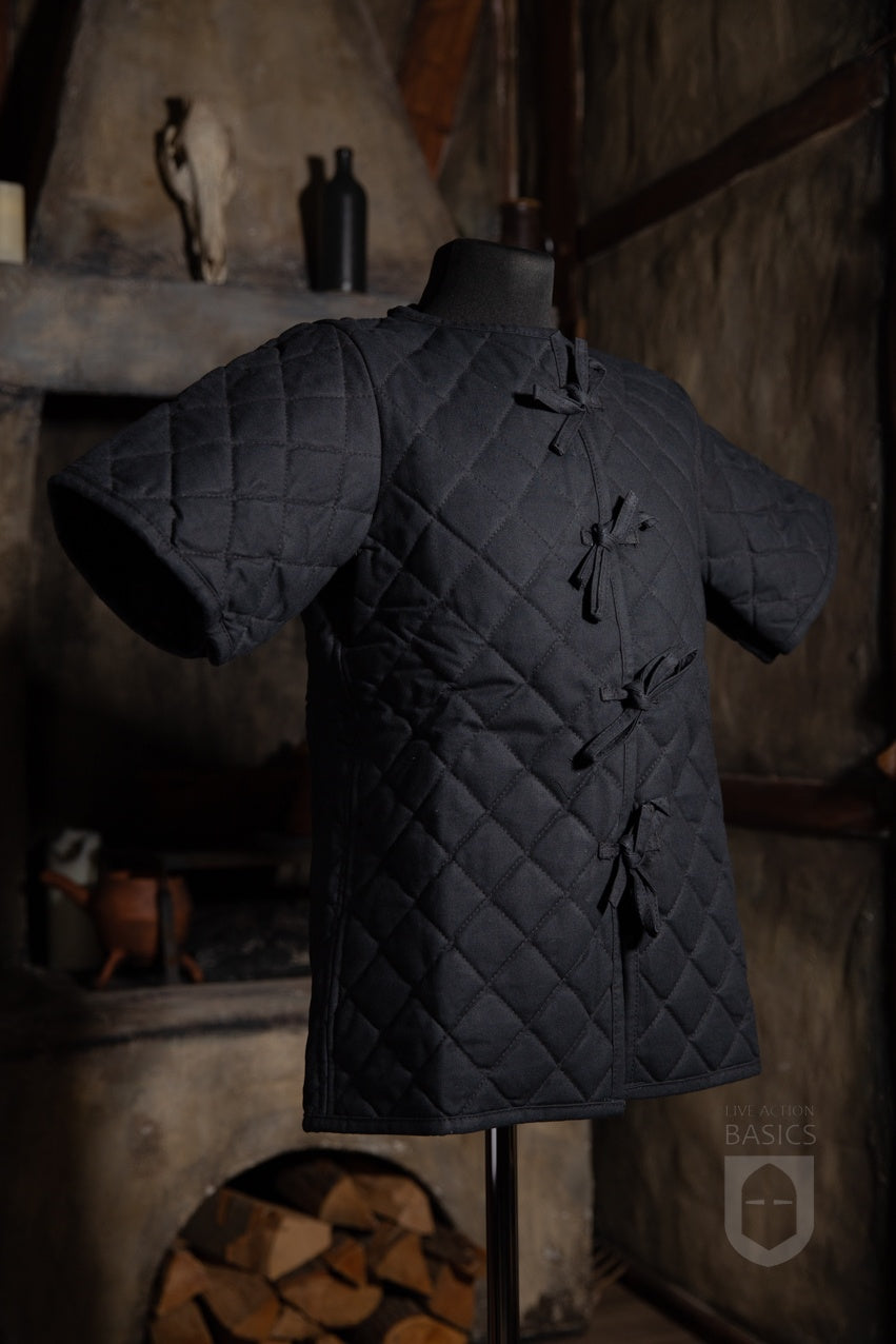 Basic Gambeson in black, featuring a quilted diamond design and front ribbons for secure tying.