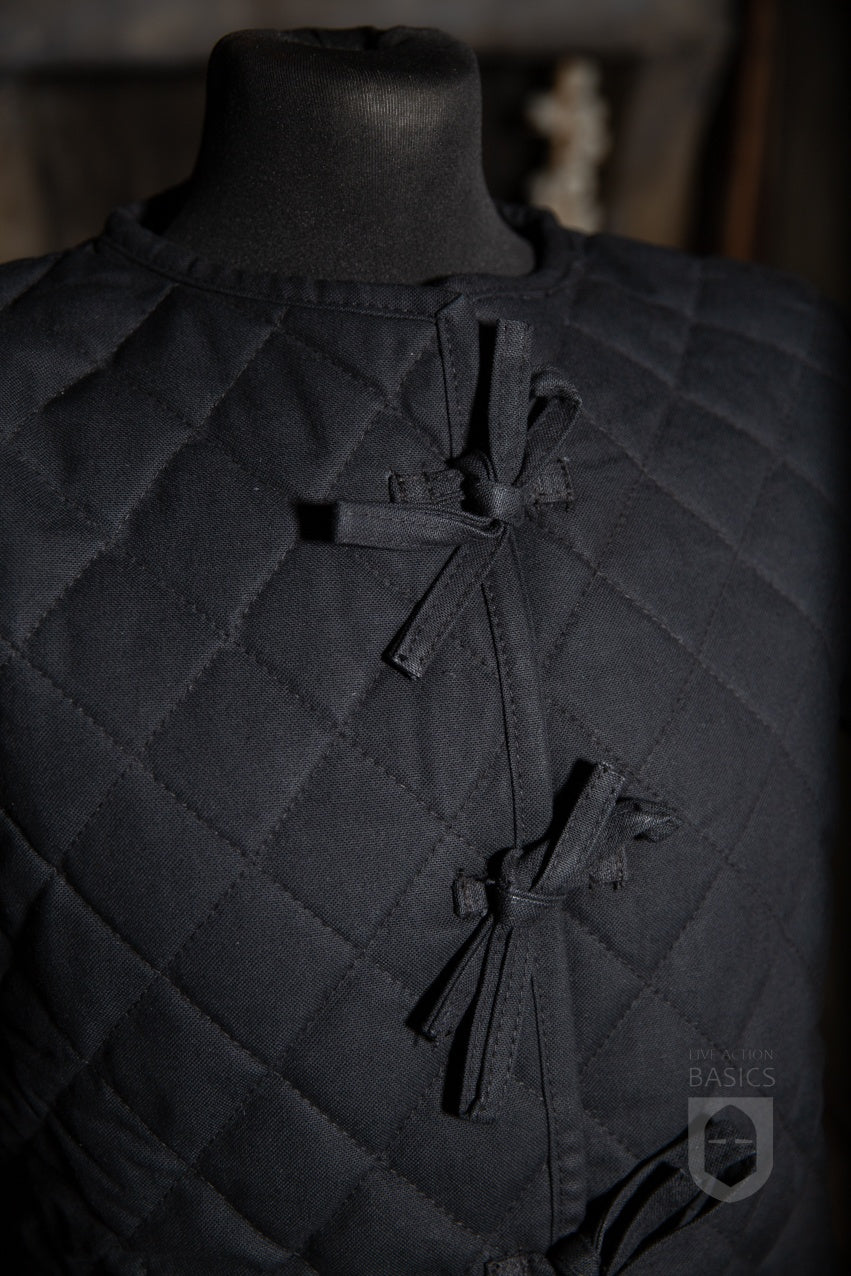 Basic Gambeson in black, featuring a quilted diamond design and front ribbons for secure tying.