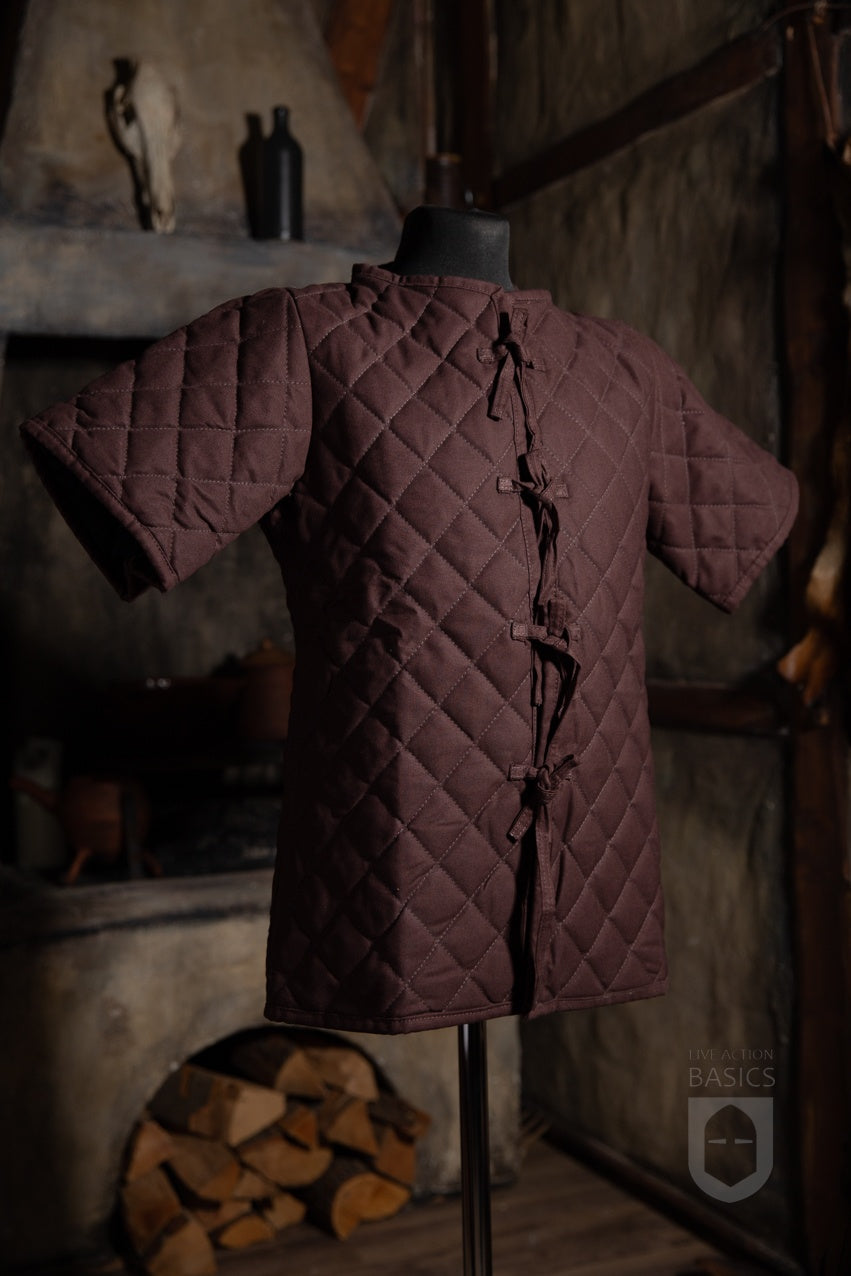 Basic Gambeson in brown color, featuring a quilted diamond design and front ribbons for tying.