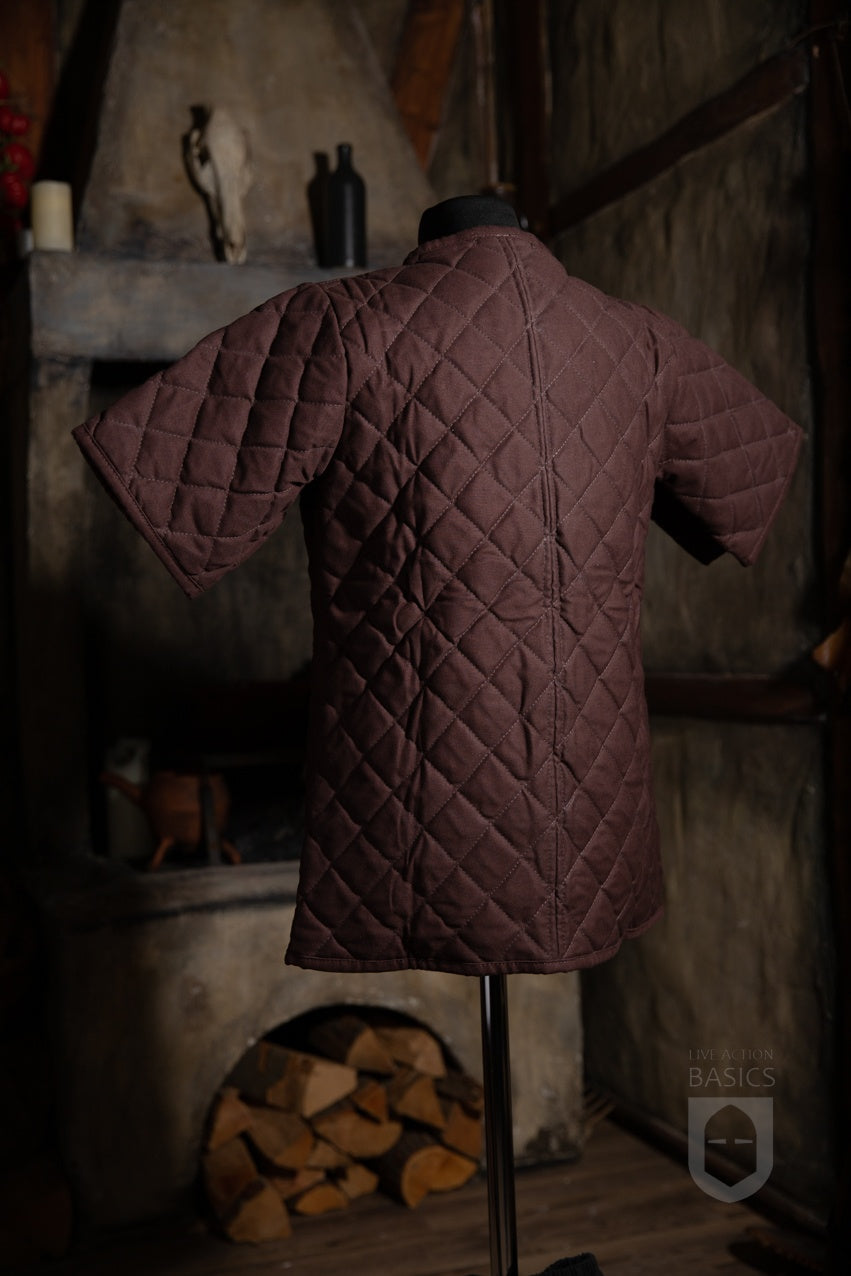 Basic Gambeson in brown color, featuring a quilted diamond design and front ribbons for tying.