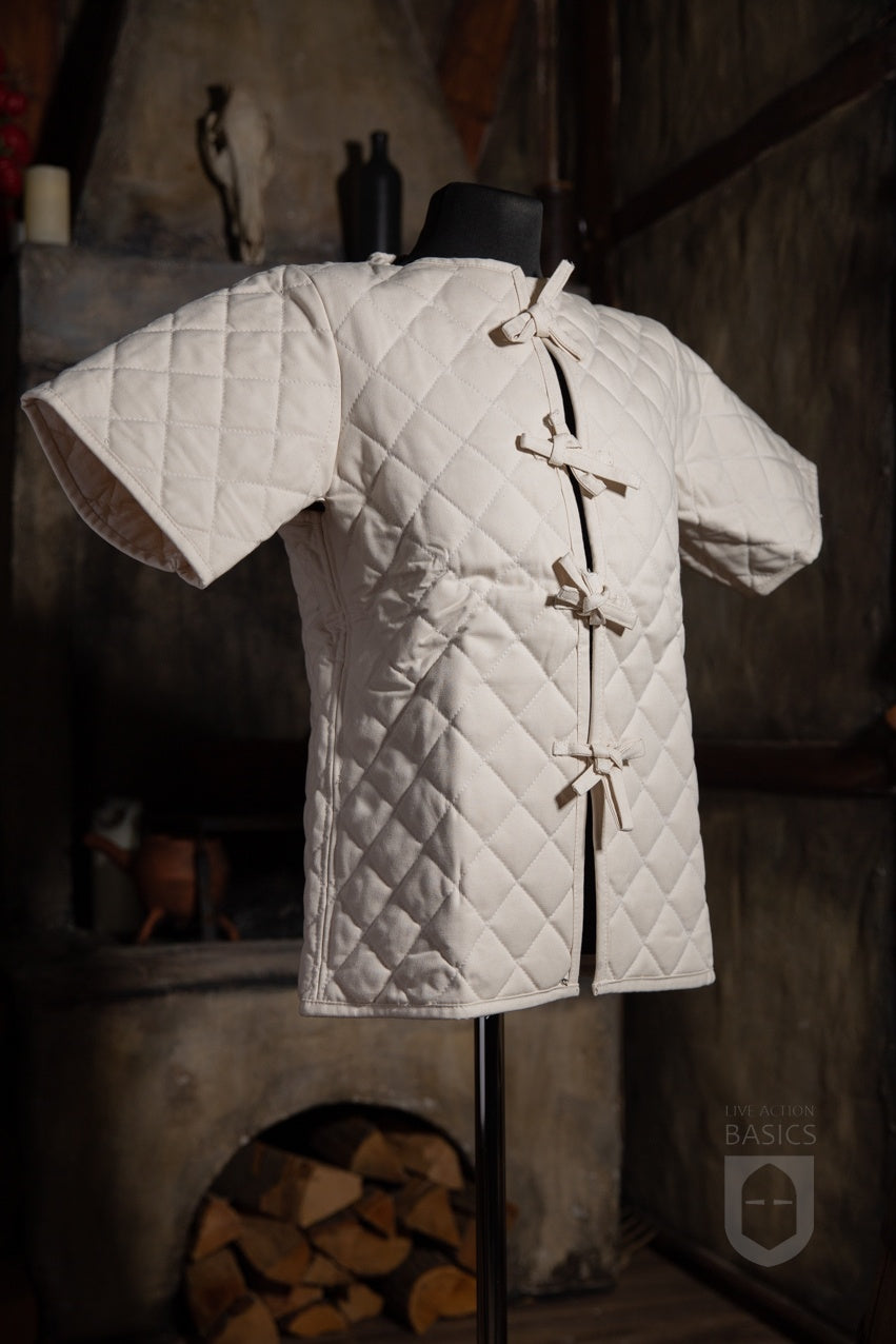 Basic Gambeson Natural made of heavy cotton canvas with a quilted diamond design and ribbons for fastening.