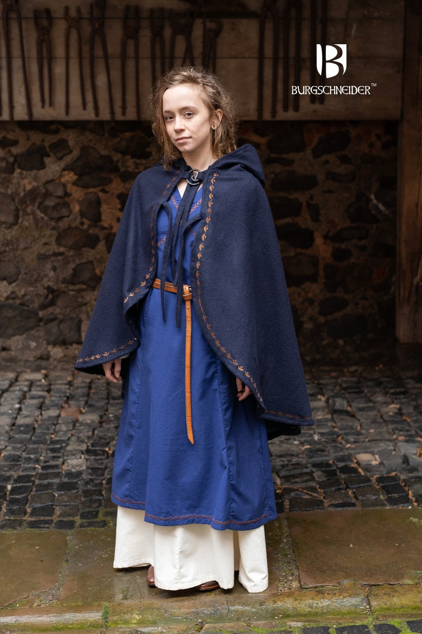 Cape Affra Blue made of wool felt with ornamental embroidery and a long pointed hood, showcasing its unique design.