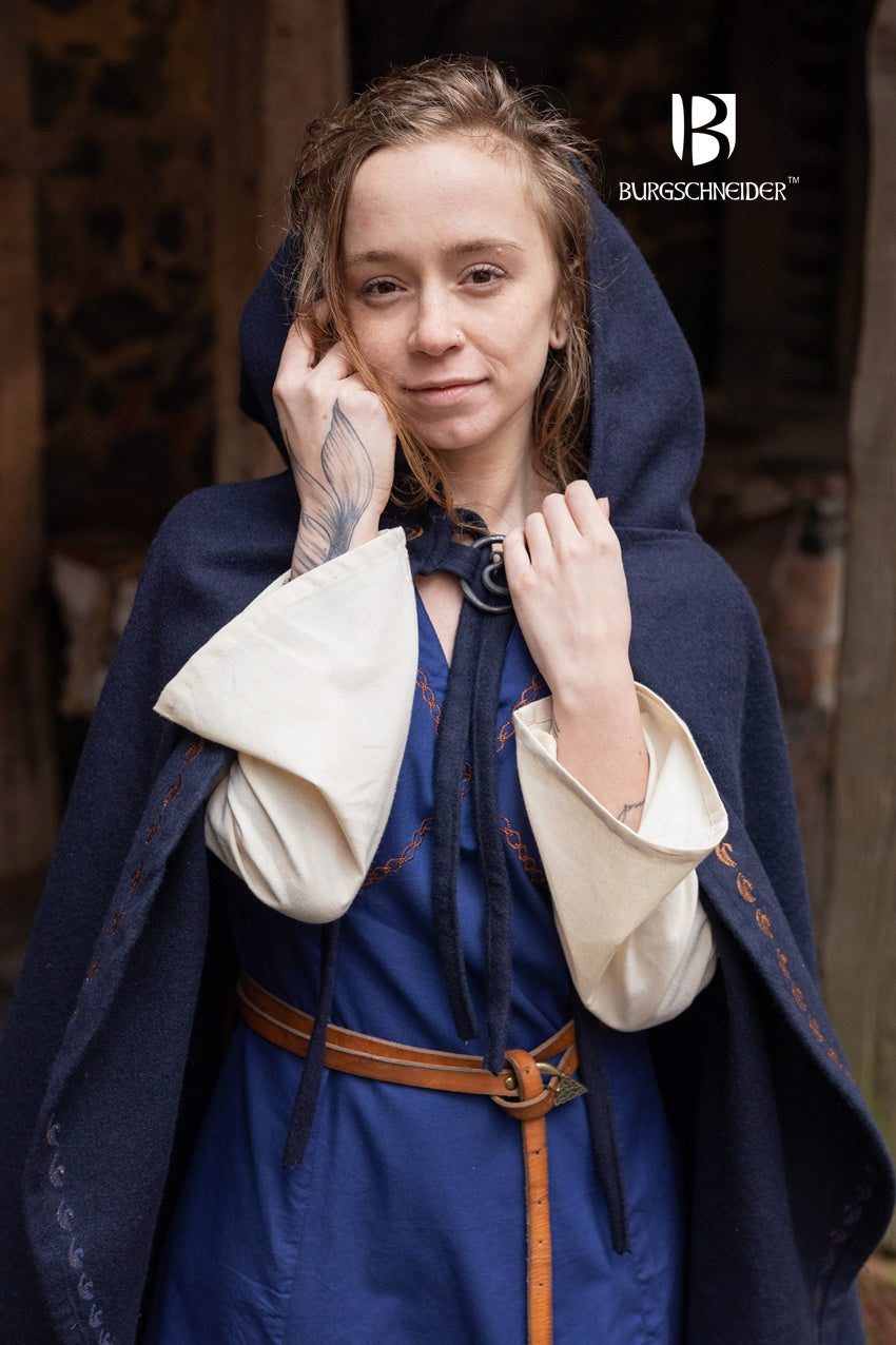 Cape Affra Blue made of wool felt with ornamental embroidery and a long pointed hood, showcasing its unique design.