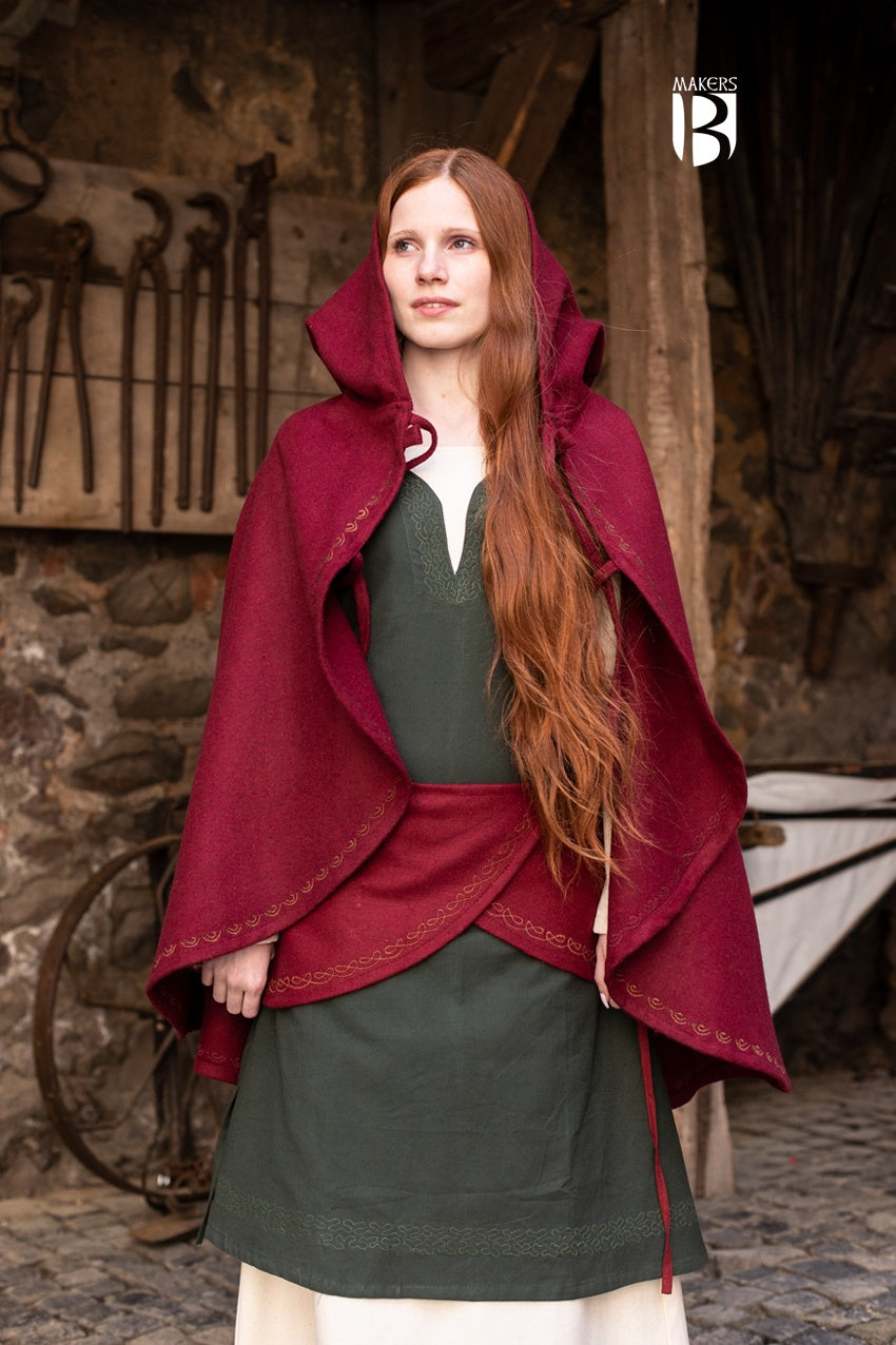 A vibrant red wool felt cape with a long pointed hood and ornamental embroidery, showcasing its unique design and double lacing closure.