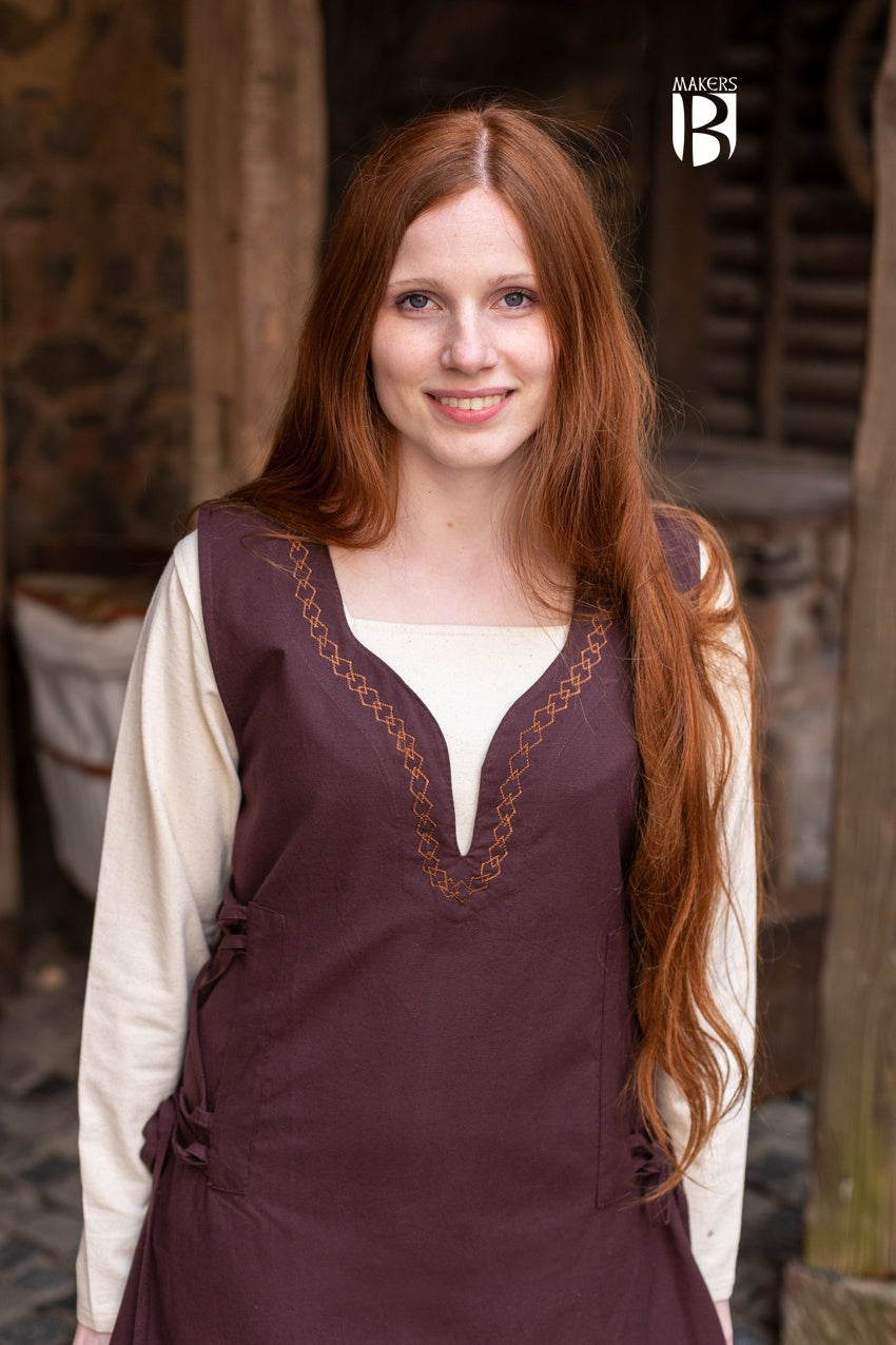 Elegant light brown sleeveless dress with side lacing and ornamental embroidery, flowing design inspired by medieval bliaut.