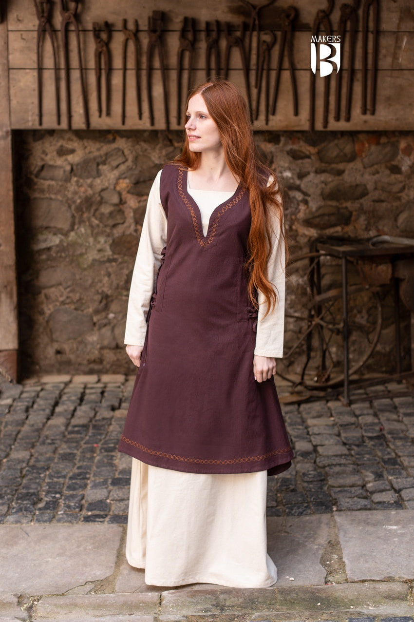 Elegant light brown sleeveless dress with side lacing and ornamental embroidery, flowing design inspired by medieval bliaut.