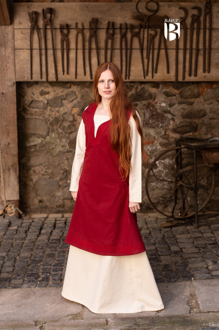 A beautiful red sleeveless dress made of fine cotton, featuring side lacing, ornamental embroidery at the neckline and hem, and a flowing design.