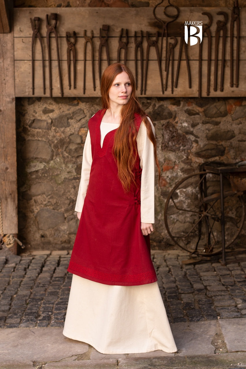 A beautiful red sleeveless dress made of fine cotton, featuring side lacing, ornamental embroidery at the neckline and hem, and a flowing design.