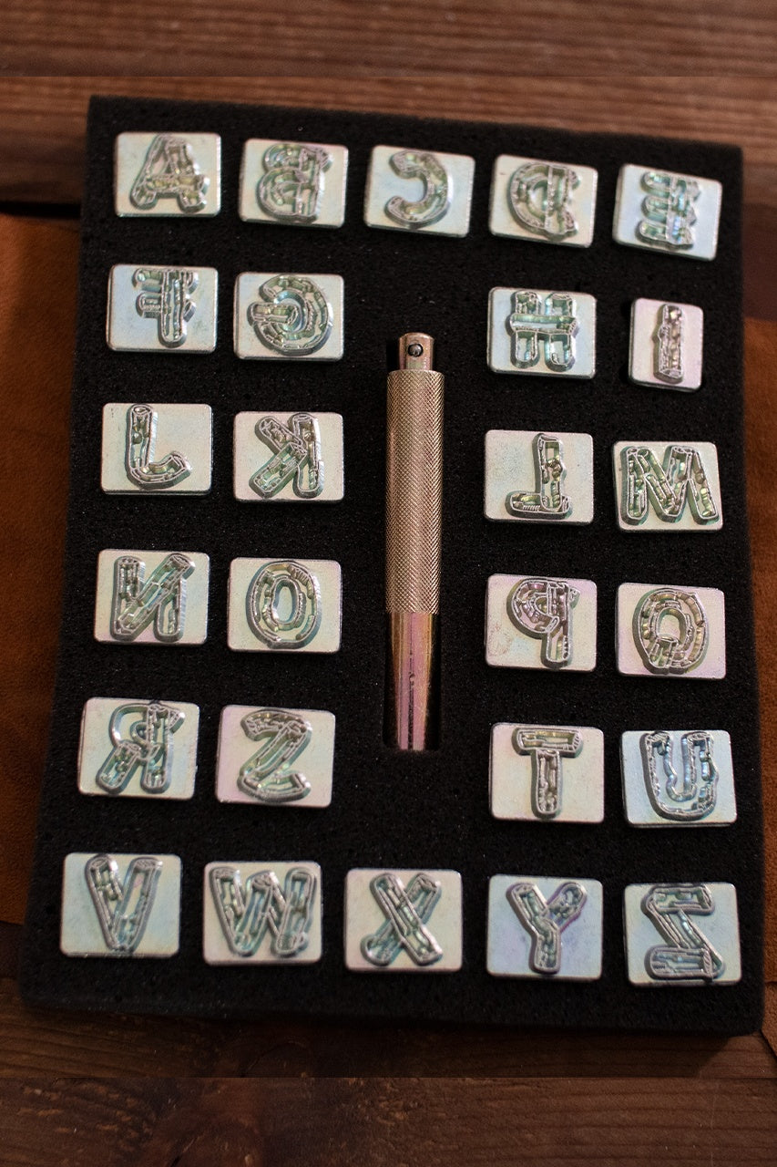 Embossing Tool Set Alphabet WOODSHAPE featuring 26 iron stamps and an iron handle for leather crafting.