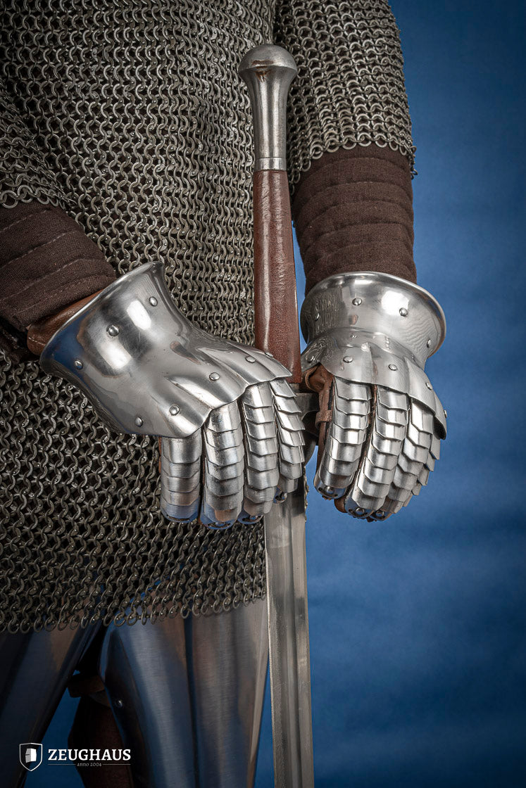 A pair of polished steel gauntlets from 1350-1415, showcasing intricate craftsmanship and an hourglass design for flexibility.