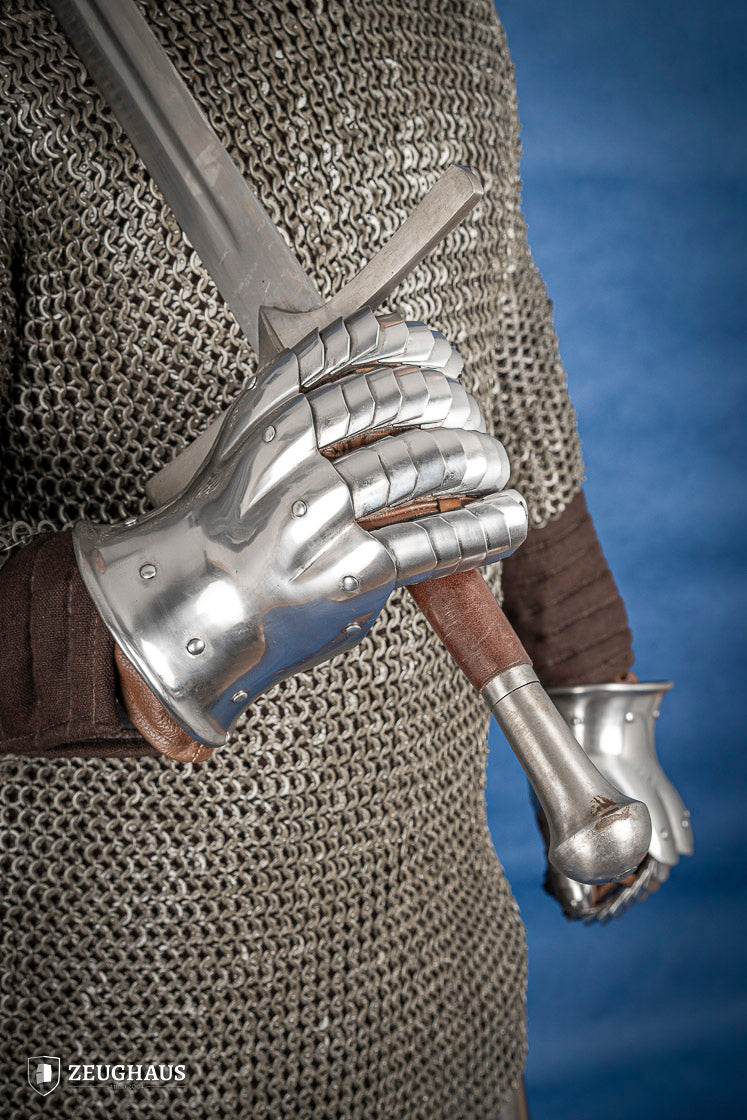 A pair of polished steel gauntlets from 1350-1415, showcasing intricate craftsmanship and an hourglass design for flexibility.