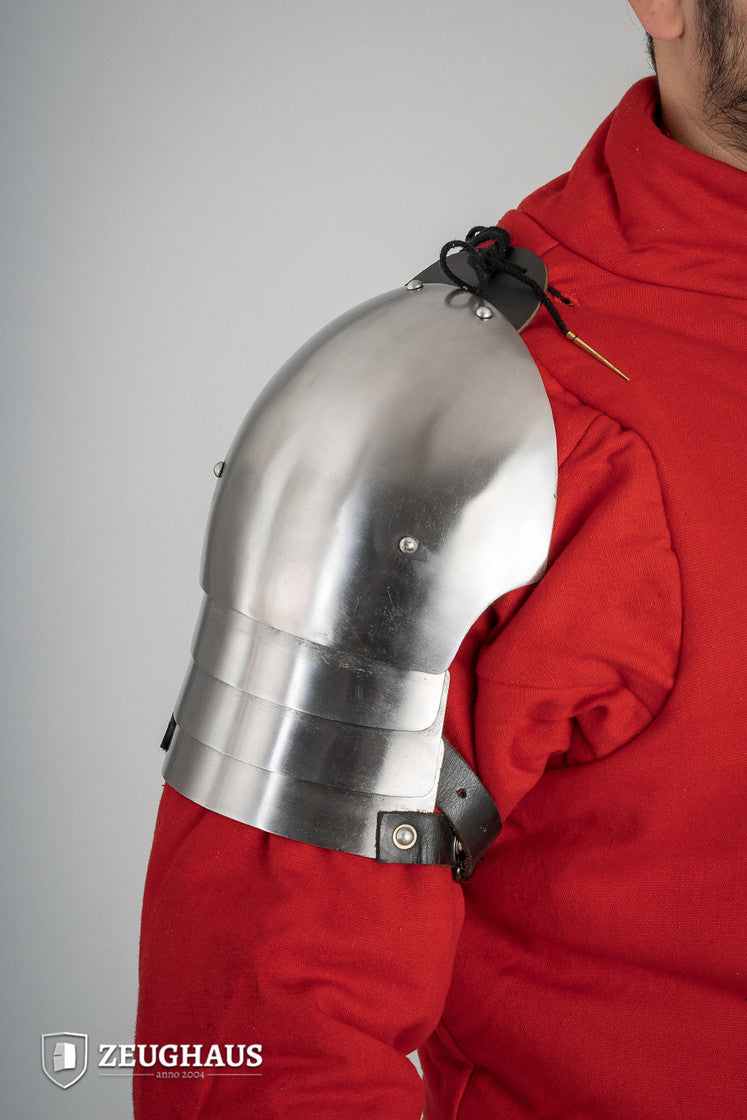 Polished 14th Century pauldrons made of 1.6mm steel, showcasing intricate design and sturdy leather cords for attachment.