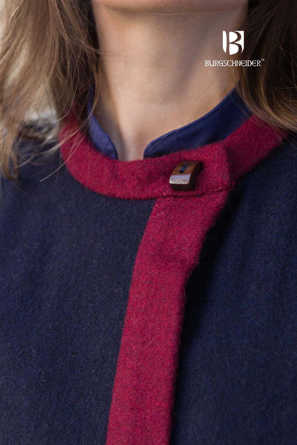 Kseniya Rus Coat featuring a deep blue fabric with vibrant red accents on the collar, cuffs, and hem, adorned with buttons for closure.