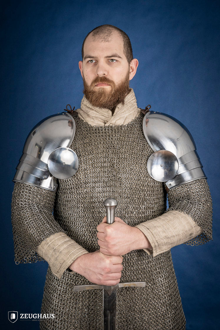 Polished medieval armored shoulders made of 1.6mm steel with a satin finish, showcasing handcrafted details and protective design.