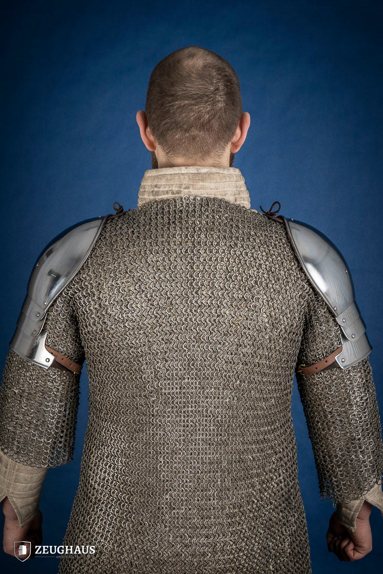 Polished medieval armored shoulders made of 1.6mm steel with a satin finish, showcasing handcrafted details and protective design.