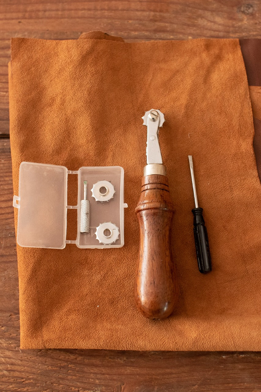 Spacer Tool for seam holes featuring three iron wheels and a brown wooden handle, designed for precise seam spacing in sewing projects.