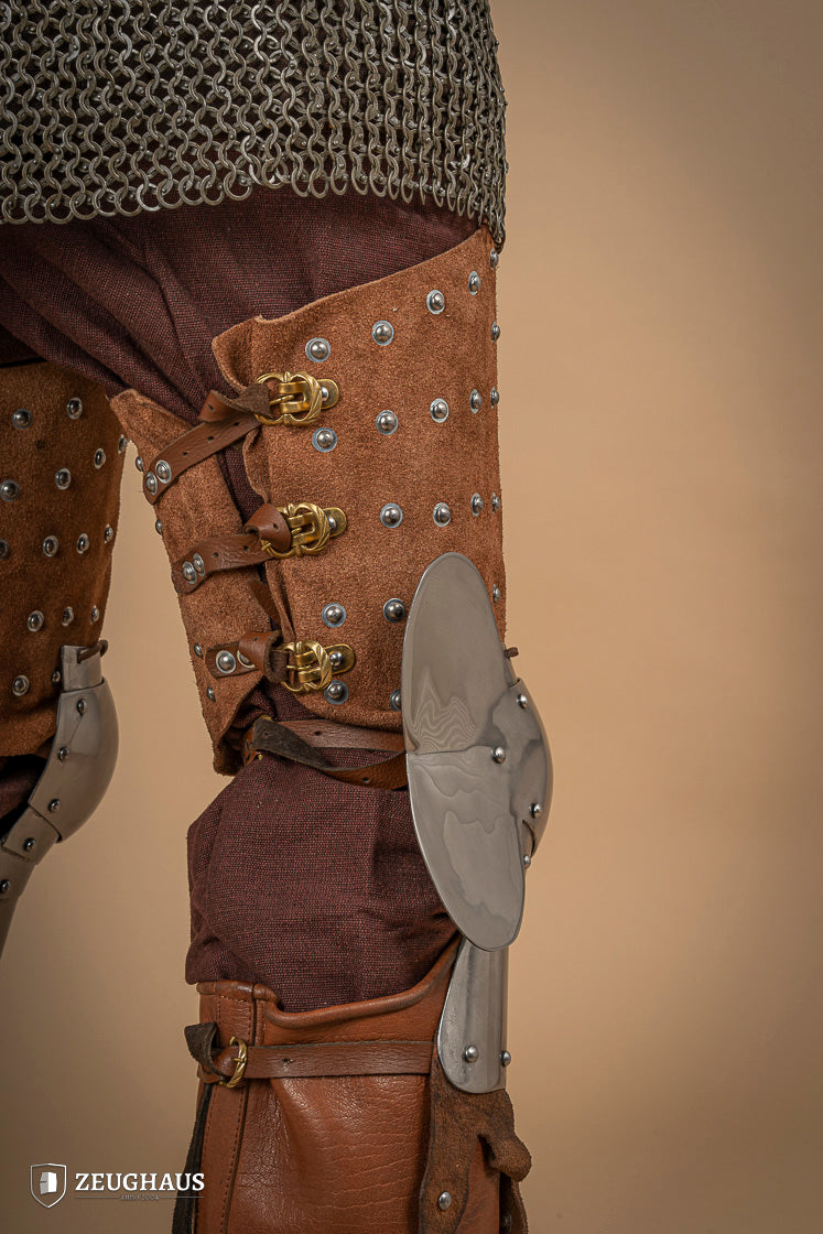 Splinted Leg Armour made of brown suede leather with steel bands, showcasing intricate craftsmanship and medieval design.