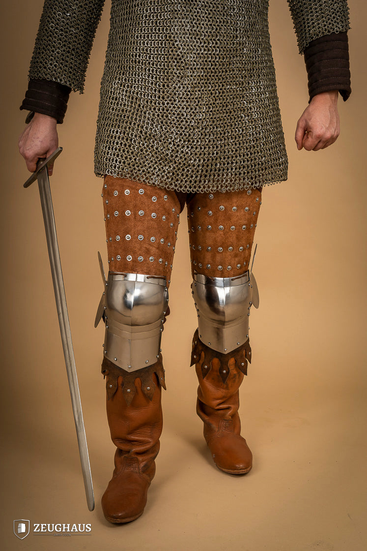 Splinted Leg Armour made of brown suede leather with steel bands, showcasing intricate craftsmanship and medieval design.