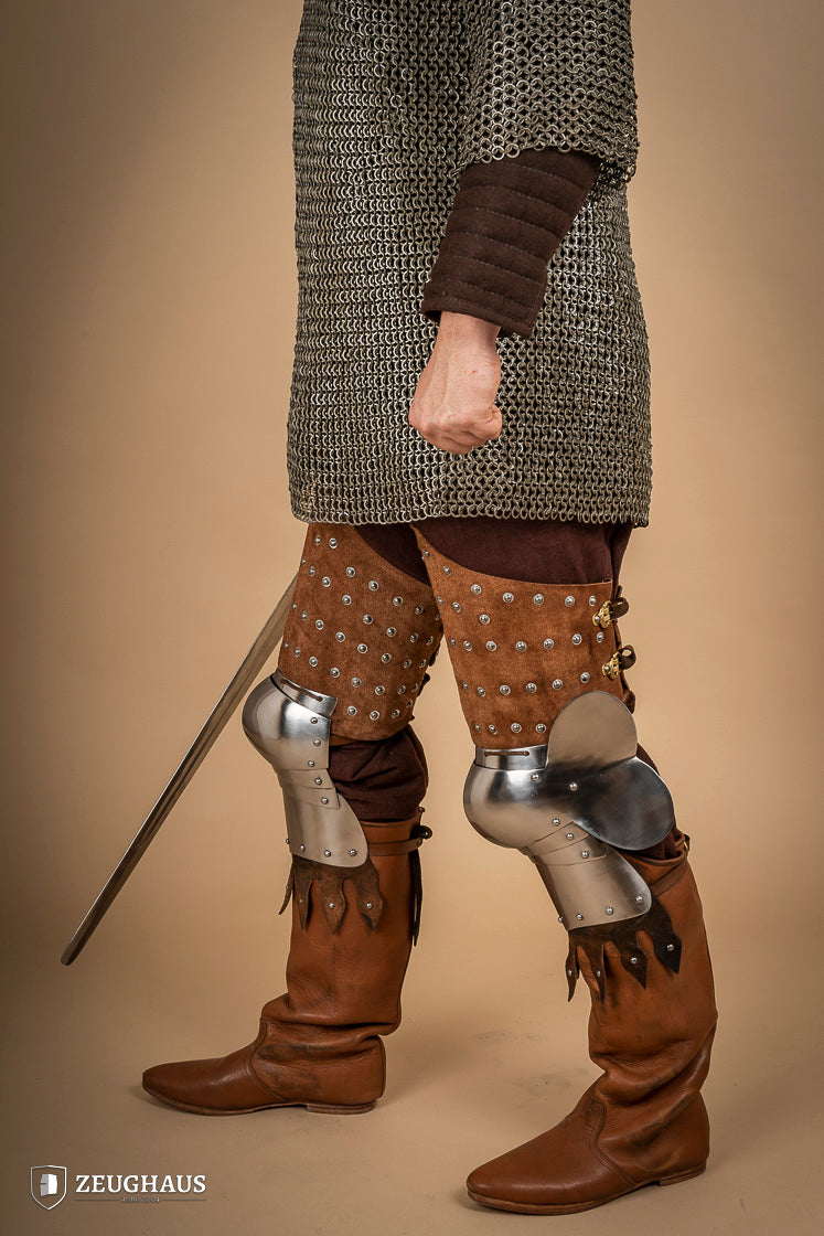 Splinted Leg Armour made of brown suede leather with steel bands, showcasing intricate craftsmanship and medieval design.