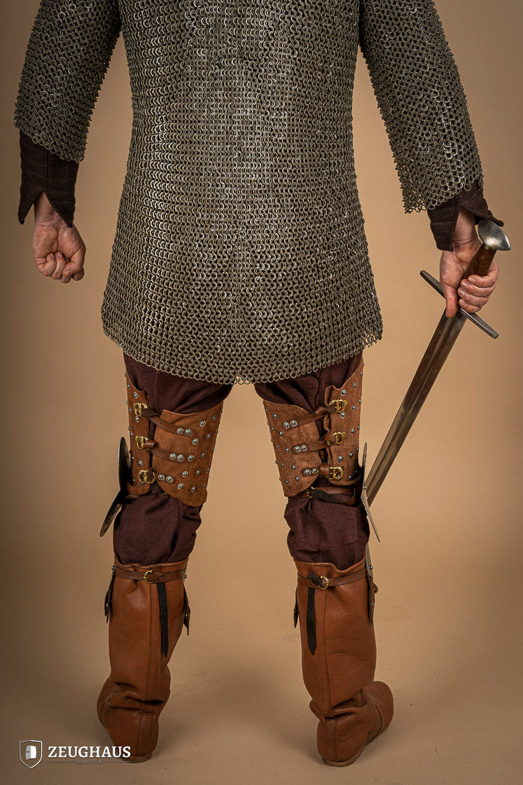 Splinted Leg Armour made of brown suede leather with steel bands, showcasing intricate craftsmanship and medieval design.