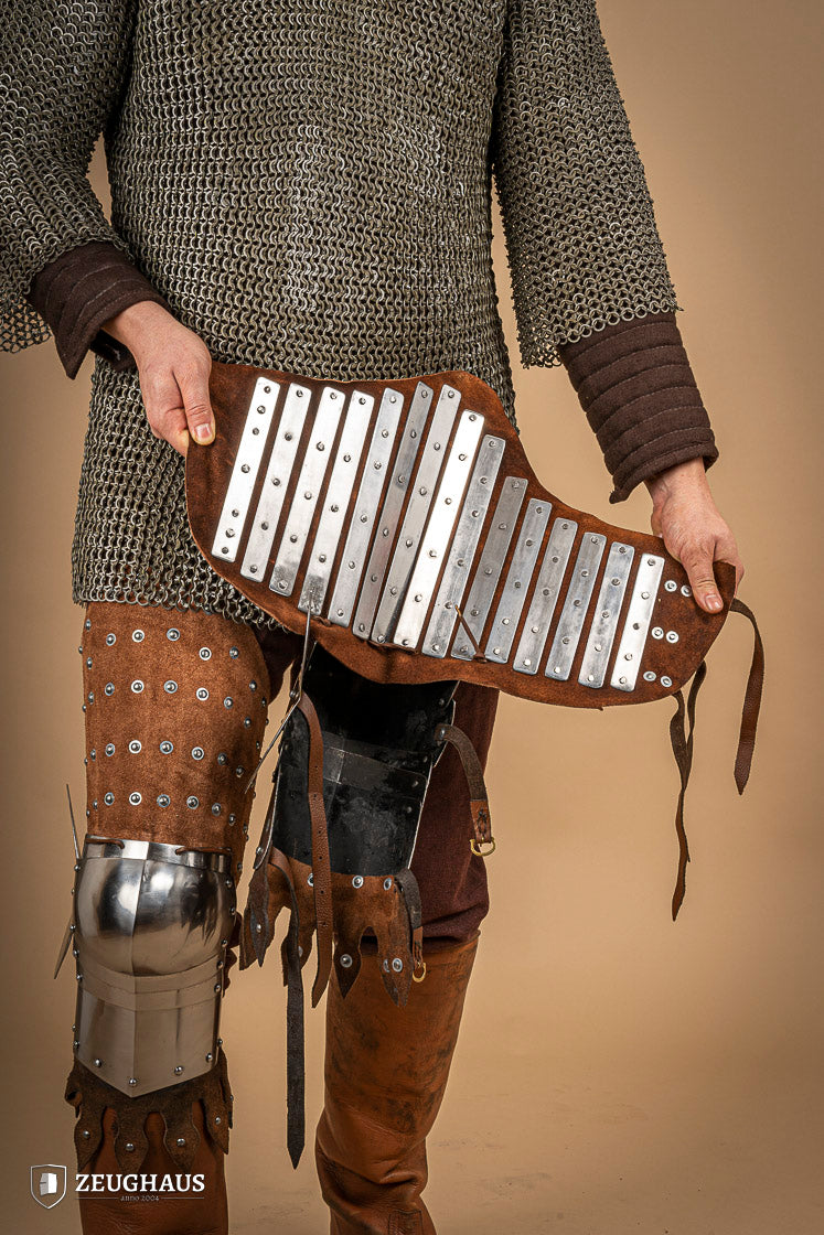 Splinted Leg Armour made of brown suede leather with steel bands, showcasing intricate craftsmanship and medieval design.