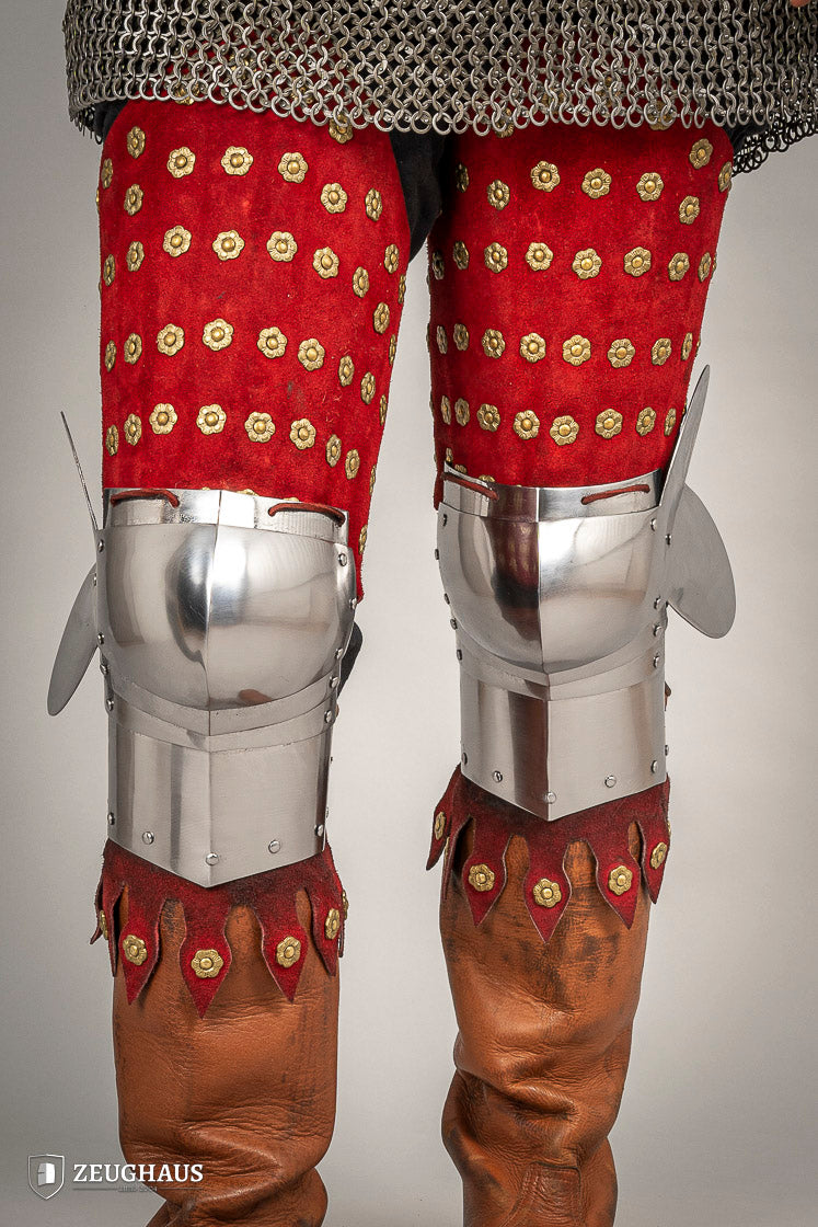 Splinted Leg Armour made of red suede leather with metal bands, showcasing intricate craftsmanship and historical design.