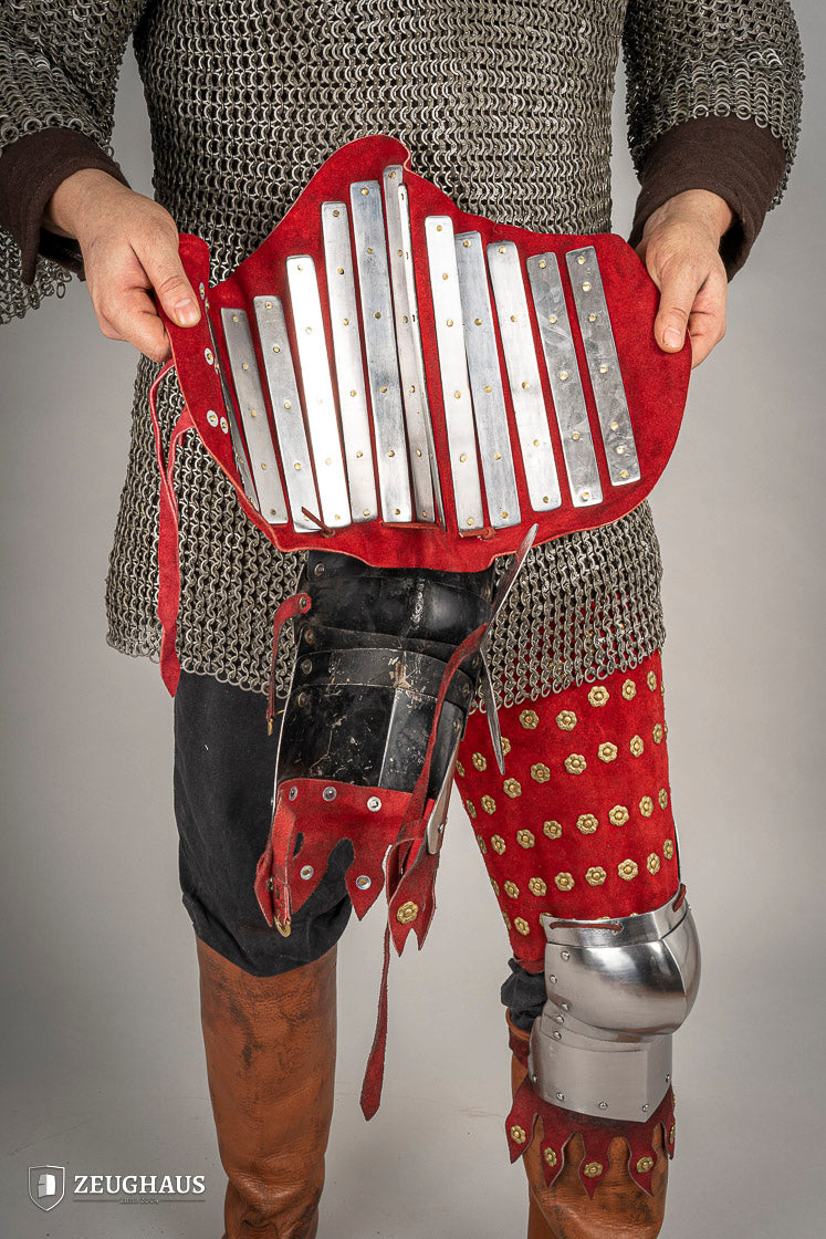 Splinted Leg Armour made of red suede leather with metal bands, showcasing intricate craftsmanship and historical design.