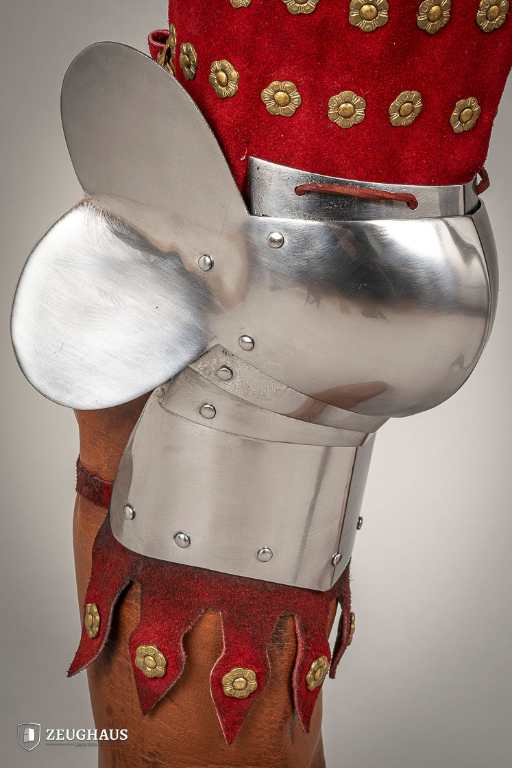 Splinted Leg Armour made of red suede leather with metal bands, showcasing intricate craftsmanship and historical design.