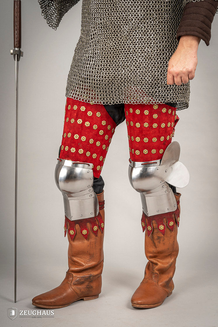 Splinted Leg Armour made of red suede leather with metal bands, showcasing intricate craftsmanship and historical design.