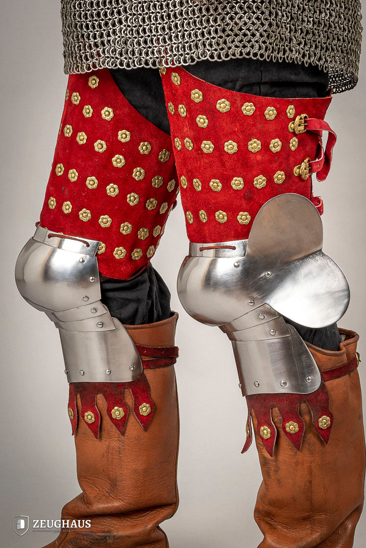 Splinted Leg Armour made of red suede leather with metal bands, showcasing intricate craftsmanship and historical design.