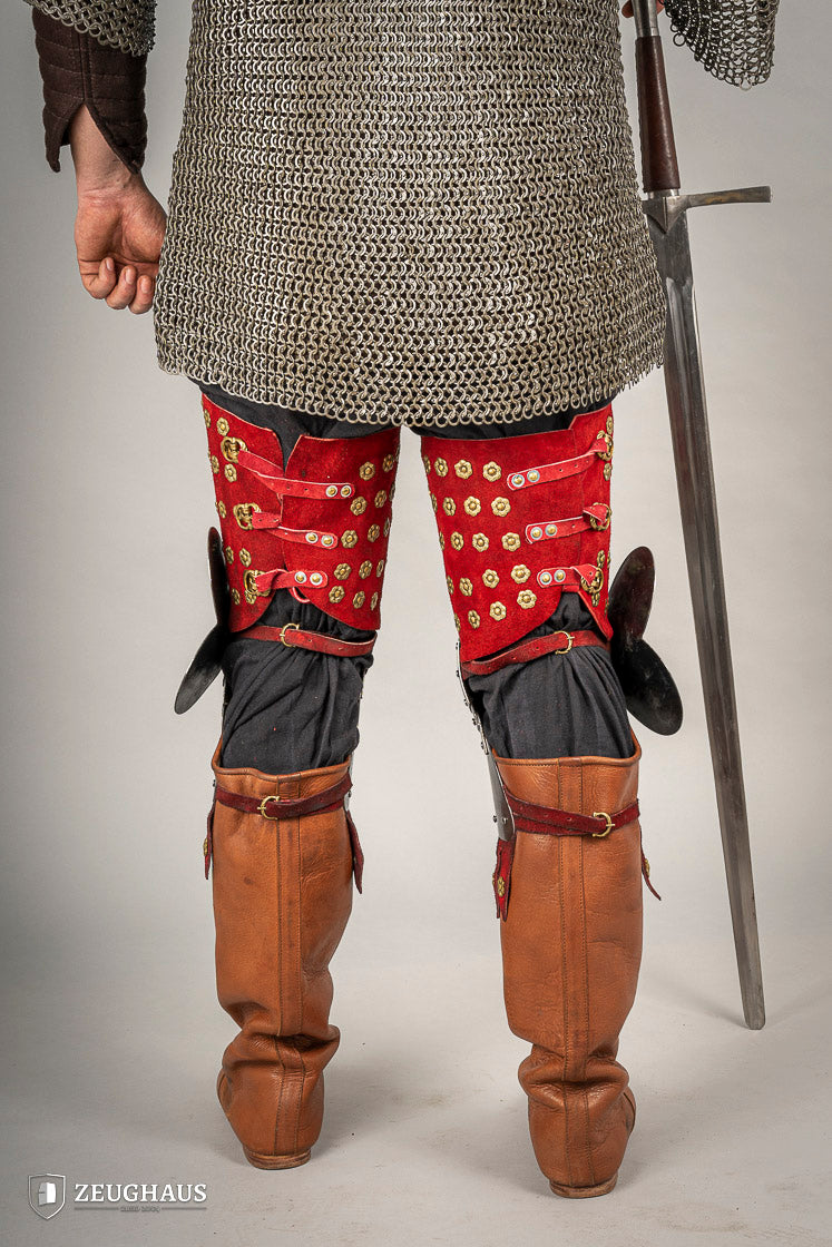 Splinted Leg Armour made of red suede leather with metal bands, showcasing intricate craftsmanship and historical design.