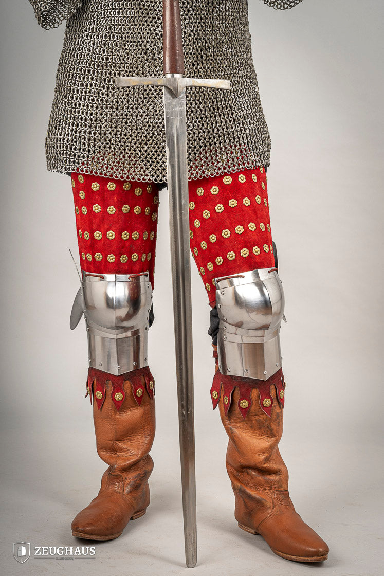 Splinted Leg Armour made of red suede leather with metal bands, showcasing intricate craftsmanship and historical design.