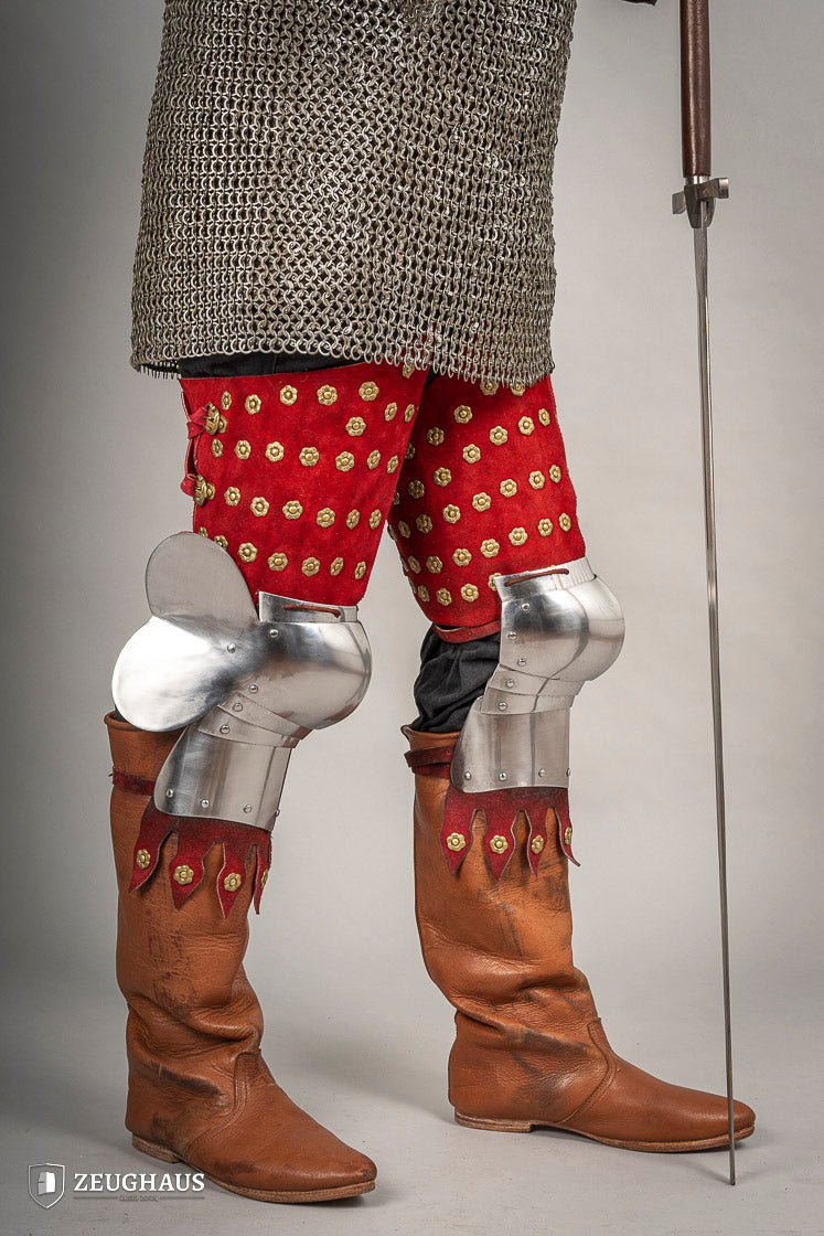 Splinted Leg Armour made of red suede leather with metal bands, showcasing intricate craftsmanship and historical design.
