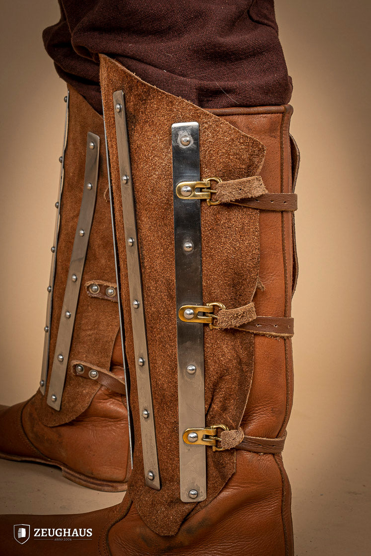 Brown suede leather greaves with riveted metal bands, showcasing a unique three-piece design for shin protection.