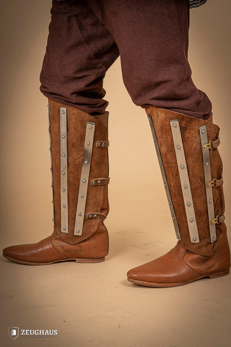 Brown suede leather greaves with riveted metal bands, showcasing a unique three-piece design for shin protection.