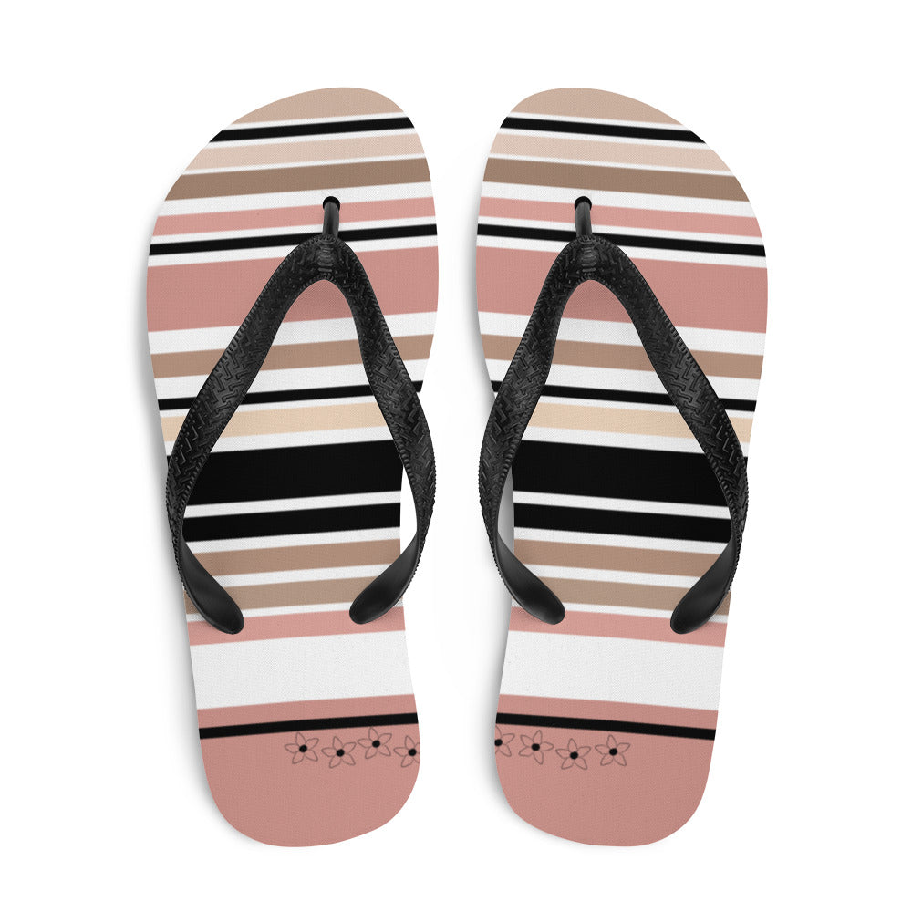 Striped beige, black, and cream flip flops with flower detail, featuring black rubber straps and a soft fabric lining, perfect for summer beach outings.