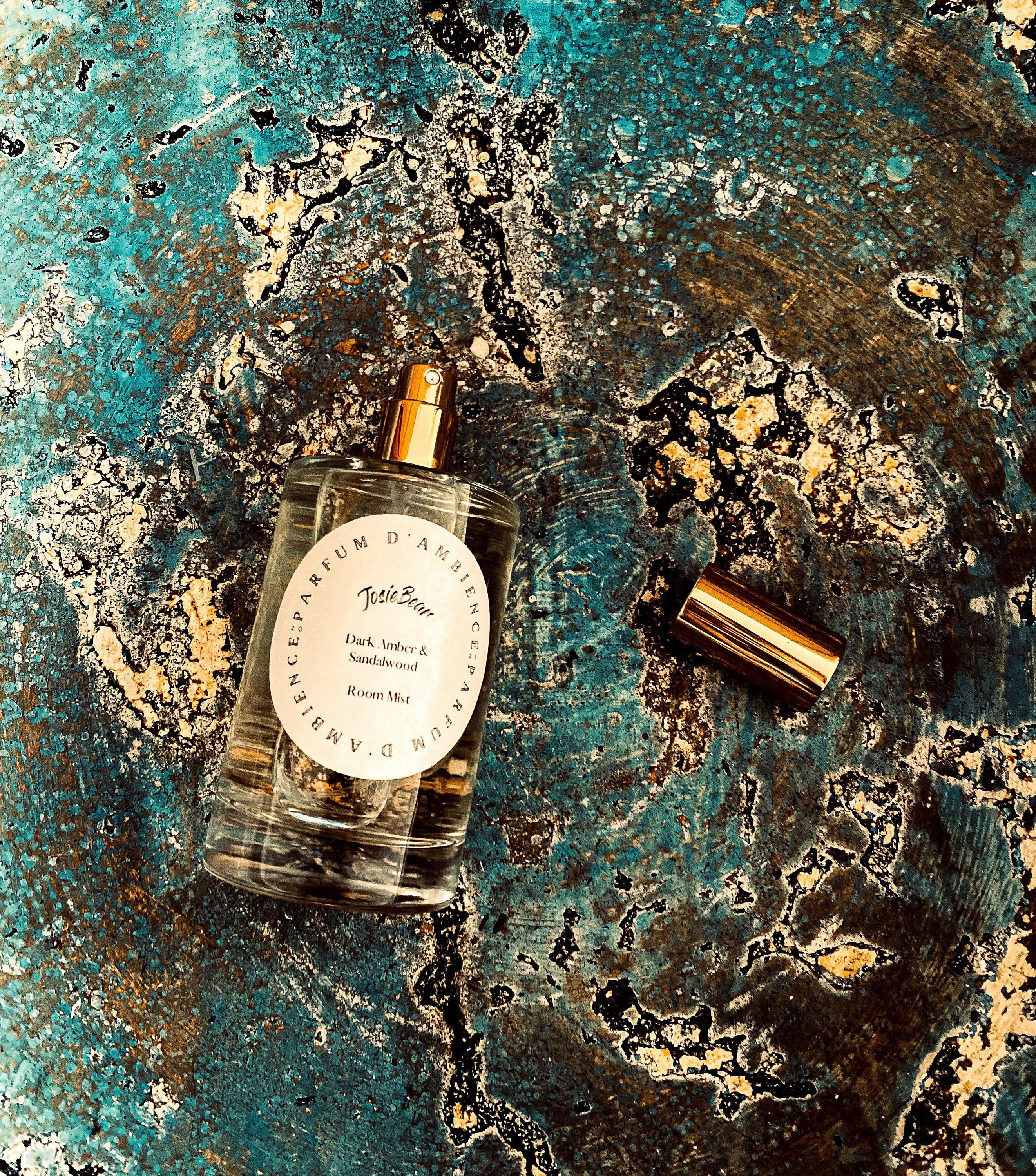 Dark Amber & Sandalwood Room Mist in an elegant glass bottle, showcasing its rich earthy color and luxurious design.