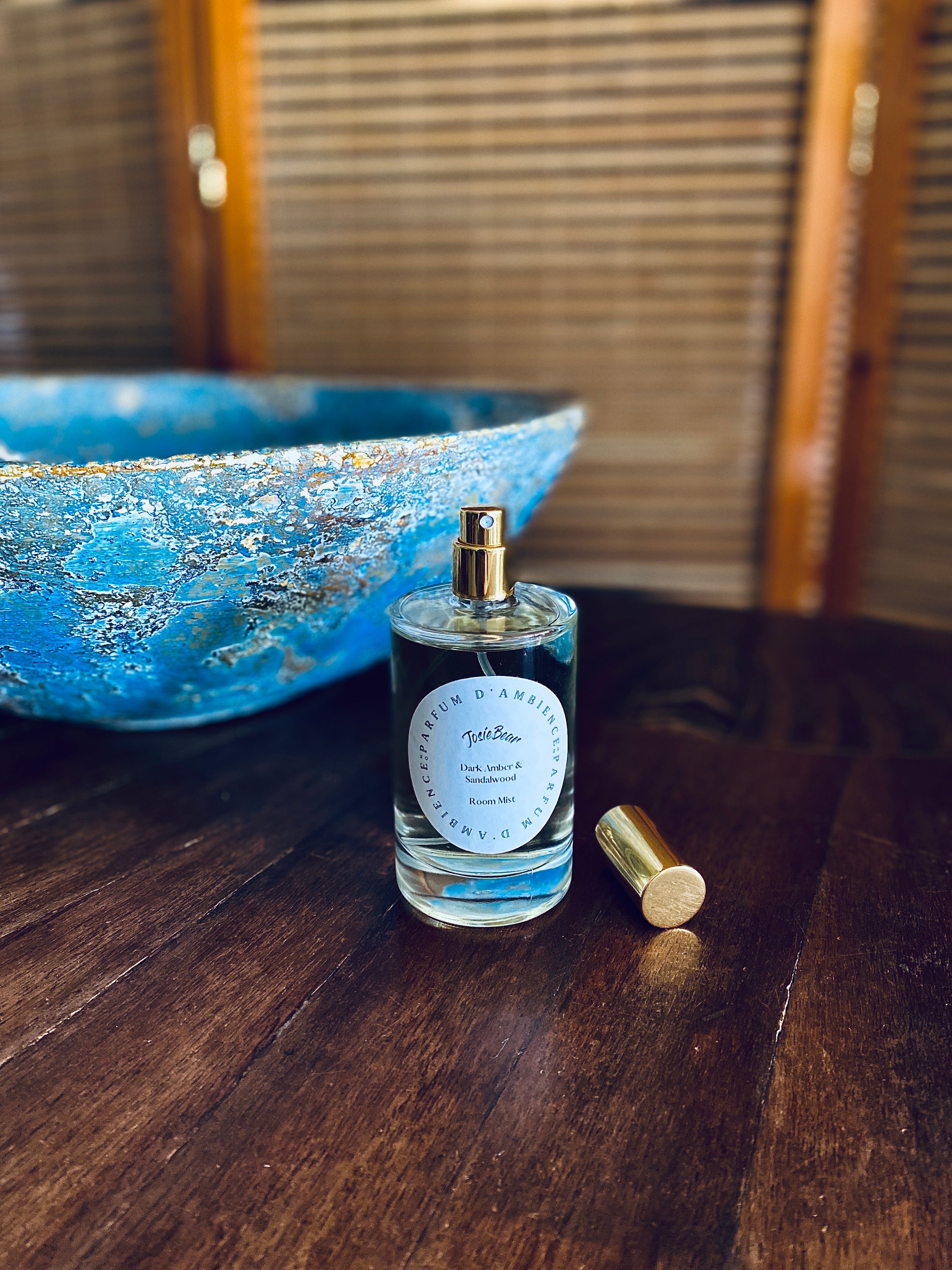 Dark Amber & Sandalwood Room Mist in an elegant glass bottle, showcasing its rich earthy color and luxurious design.