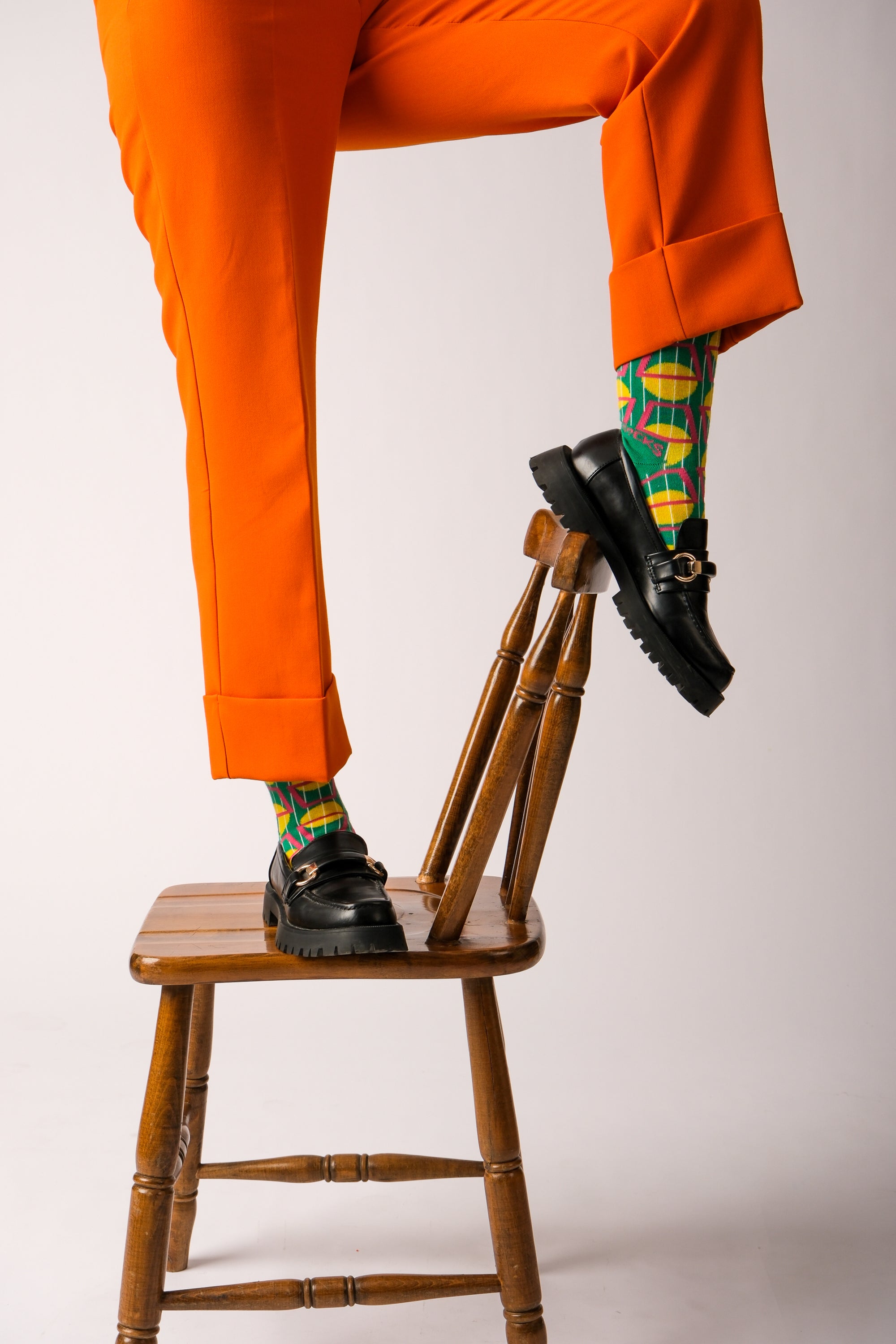 A pair of stylish green and purple geometric socks displayed together, showcasing their vibrant colors and unique patterns.