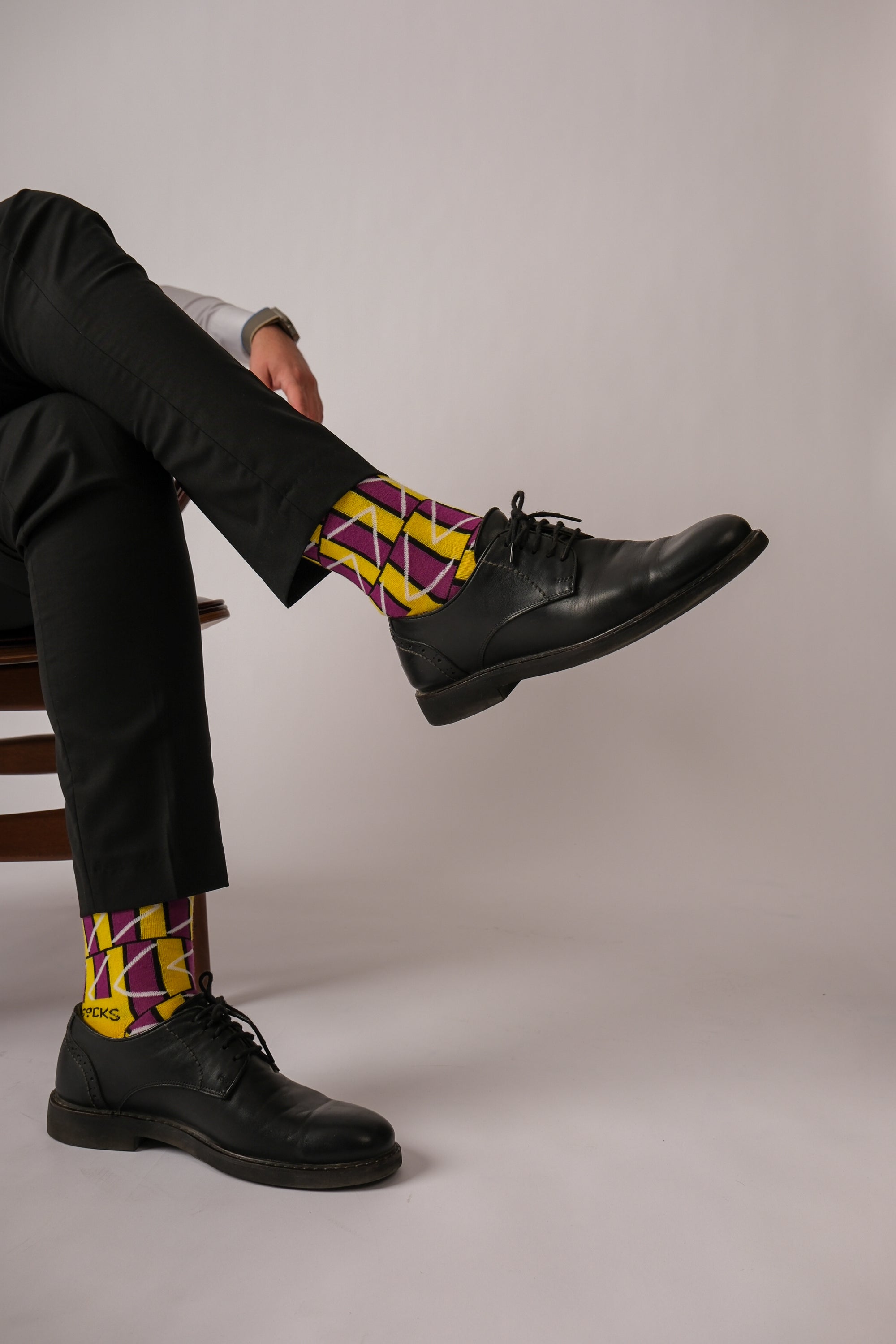 A pair of stylish green and purple geometric socks displayed together, showcasing their vibrant colors and unique patterns.