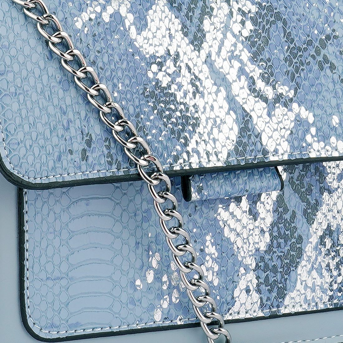 Stylish blue sling bag with reptile print texture and silver chain strap, perfect for casual daily use.