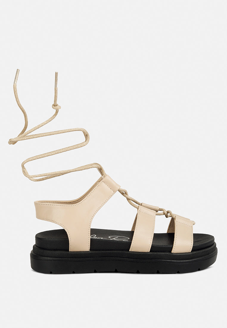 Dylan Strappy Gladiator Sandals featuring faux leather, lace-up detail, and open rounded toe design.