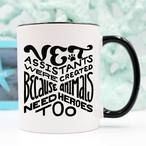 A humorous 11oz coffee mug featuring the phrase 'Vet Assistants Were Created Because Animals Need Heroes Too', designed for animal lovers.