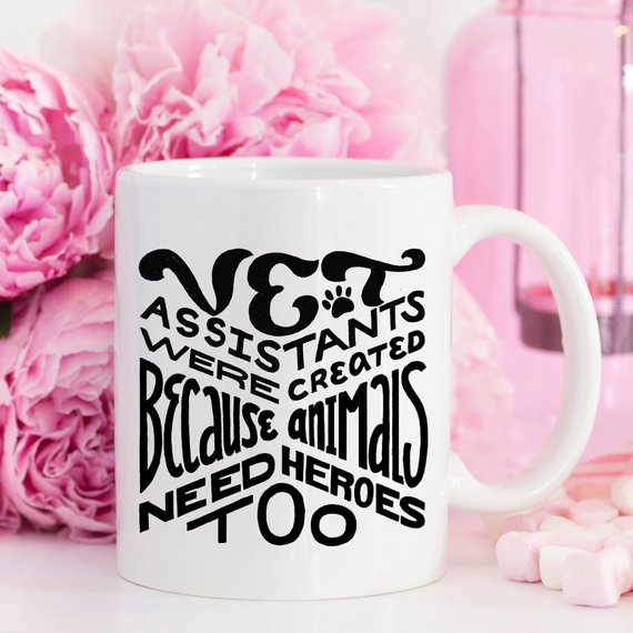 A humorous 11oz coffee mug featuring the phrase 'Vet Assistants Were Created Because Animals Need Heroes Too', designed for animal lovers.