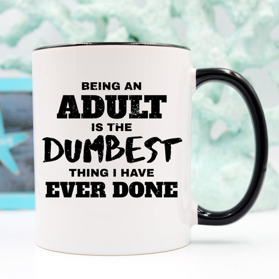 A humorous coffee mug with the phrase 'Being An Adult Is The Dumbest Thing I Have Ever Done' printed on it, showcasing a fun design.