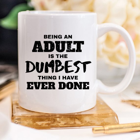 A humorous coffee mug with the phrase 'Being An Adult Is The Dumbest Thing I Have Ever Done' printed on it, showcasing a fun design.